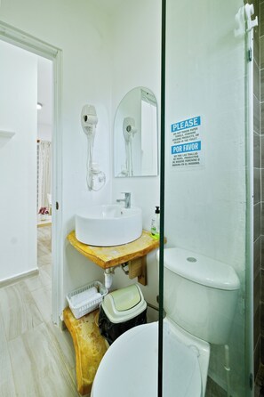 A bathroom with a white sink, mirror, and toilet. There's a sign on the wall with instructions in English and Spanish. - Peaceful 1bedroom studio with AC in charming Cabrera (Cabrera)