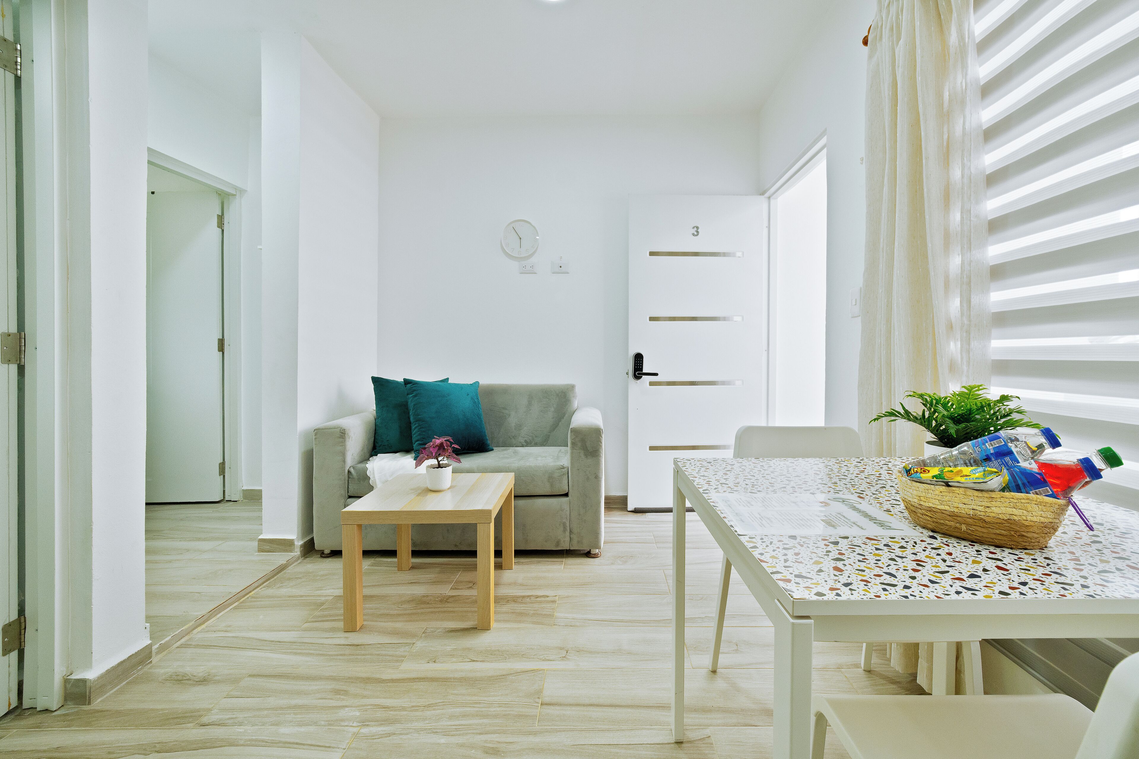 A minimalist living room with a sofa, a small table, and a dining table with a basket of items.