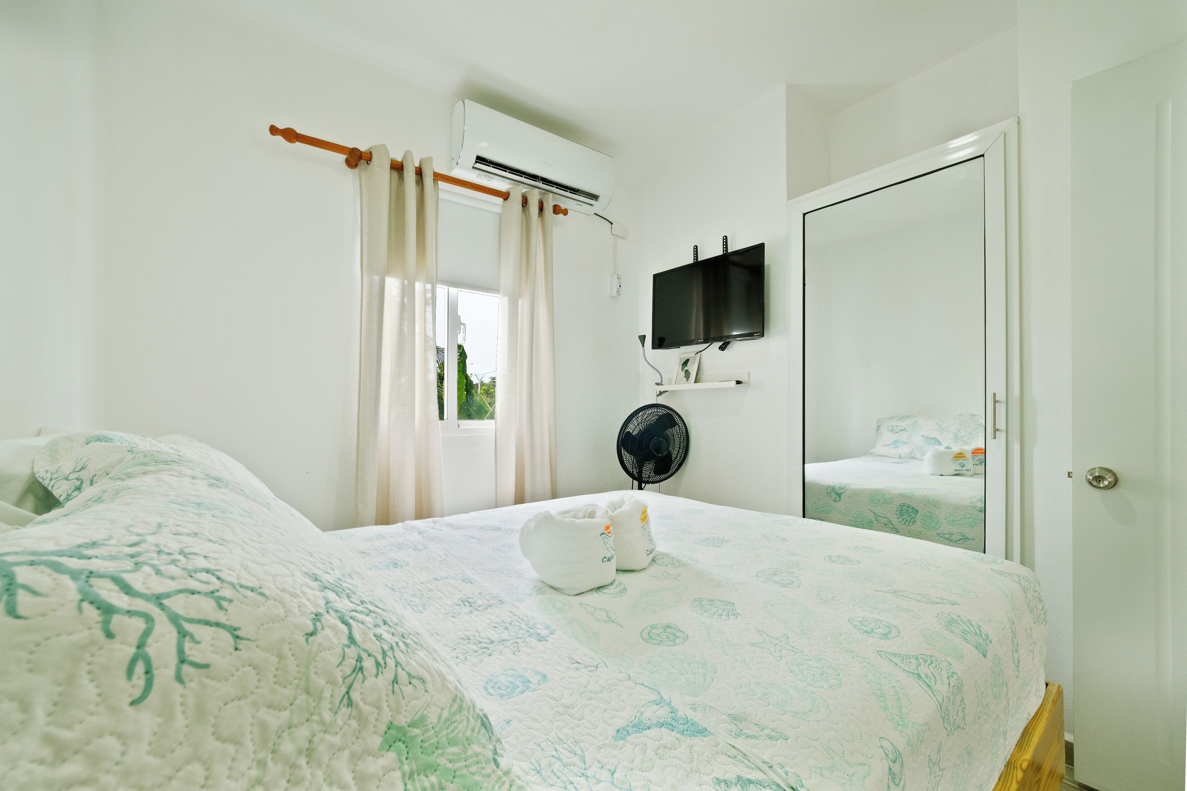 Ein Schlafzimmer mit einem Bett, einer Klimaanlage, einem Fernseher und einer Tür.