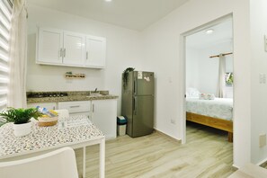 A compact kitchen with white cabinets, a stainless steel refrigerator, a small countertop, and a dining table with a placemat. - Peaceful 1bedroom studio with AC in charming Cabrera (Cabrera)