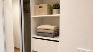 A closet with shelves, a hanging rack, and a light switch. - Ocean and Marina View · Terrace · Sleeps 4 · Riviera (Villeneuve-Loubet)