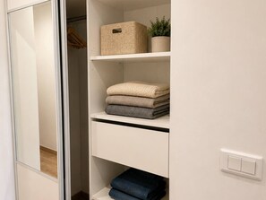 A closet with shelves, a hanging rack, and a light switch. - Ocean and Marina View · Terrace · Sleeps 4 · Riviera (Villeneuve-Loubet)