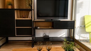 A modern living room with a flat-screen TV, a wooden coffee table, two wine glasses, a candle, and a potted plant. - Ocean and Marina View · Terrace · Sleeps 4 · Riviera (Villeneuve-Loubet)