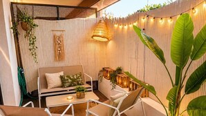 A cozy outdoor seating area with a table, chairs, and ambient lighting. - 2-Bedroom Apartment with Private Terrace · Pool · 50m from the Beach · Parking (Villeneuve-Loubet)