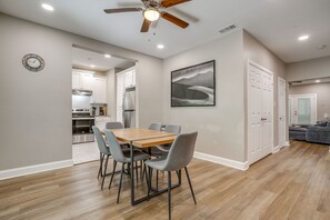 A dining area with a wooden table and chairs, a ceiling fan, and a kitchen in the background. - Spacious Dallas Home + Guest House | Sleeps 21 (Dallas)