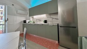 Una cocina compacta con refrigerador, microondas y cafetera sobre la encimera.