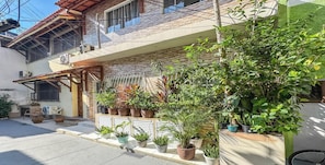 A residential building with a balcony, potted plants, and outdoor furniture. - Casa na Zona Norte do Rio proximo ao metro (Rio de Janeiro)