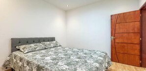 A bedroom with a bed, a wooden door, and a white ceiling. - Casa na Zona Norte do Rio proximo ao metro (Rio de Janeiro)
