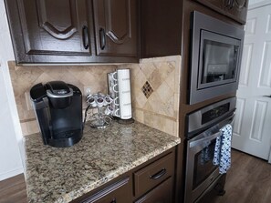 A kitchen with a coffee maker, a coffee dispenser, and a microwave. - Pool + Hot Tub | DFW Airport + Stadiums (Euless)