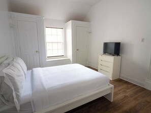 Ein Schlafzimmer mit Bett, Kommode, Fernseher und zwei Türen.