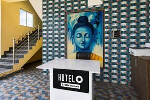 A hotel lobby with a Buddha painting, a staircase, and a sign indicating it is serviced by Oyo.