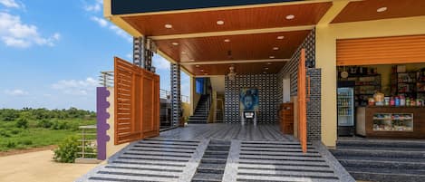 A hotel entrance with a checkered floor leading to a staircase, a visible staircase, and a wall with a Buddha statue.