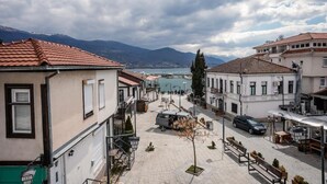 Une vue de rue avec des bâtiments, un ciel dégagé et une étendue d’eau au loin.