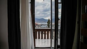 Une chambre avec un balcon, une vue sur la ville et une montagne à l’horizon.