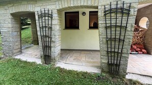 A stone building with a covered entrance, a small window, and a firewood stack.