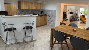 A modern kitchen with wooden cabinets, a bar stool, and a dining table with chairs.