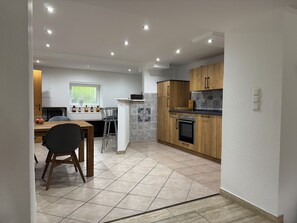 Eine moderne Küche mit Holzschränken, einem eingebauten Ofen und einem Essbereich mit Tisch und Stühlen.