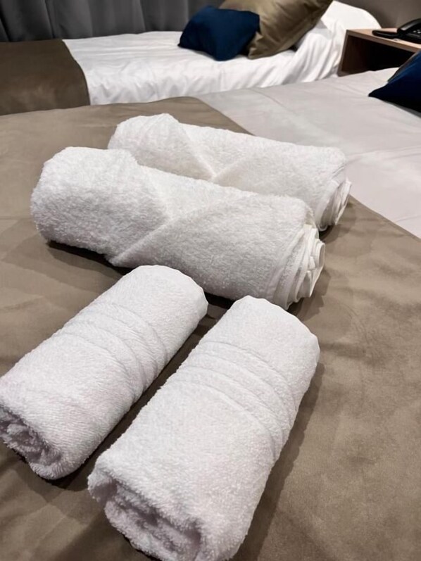 A bed with white towels, a brown headboard, and a blue pillow.
