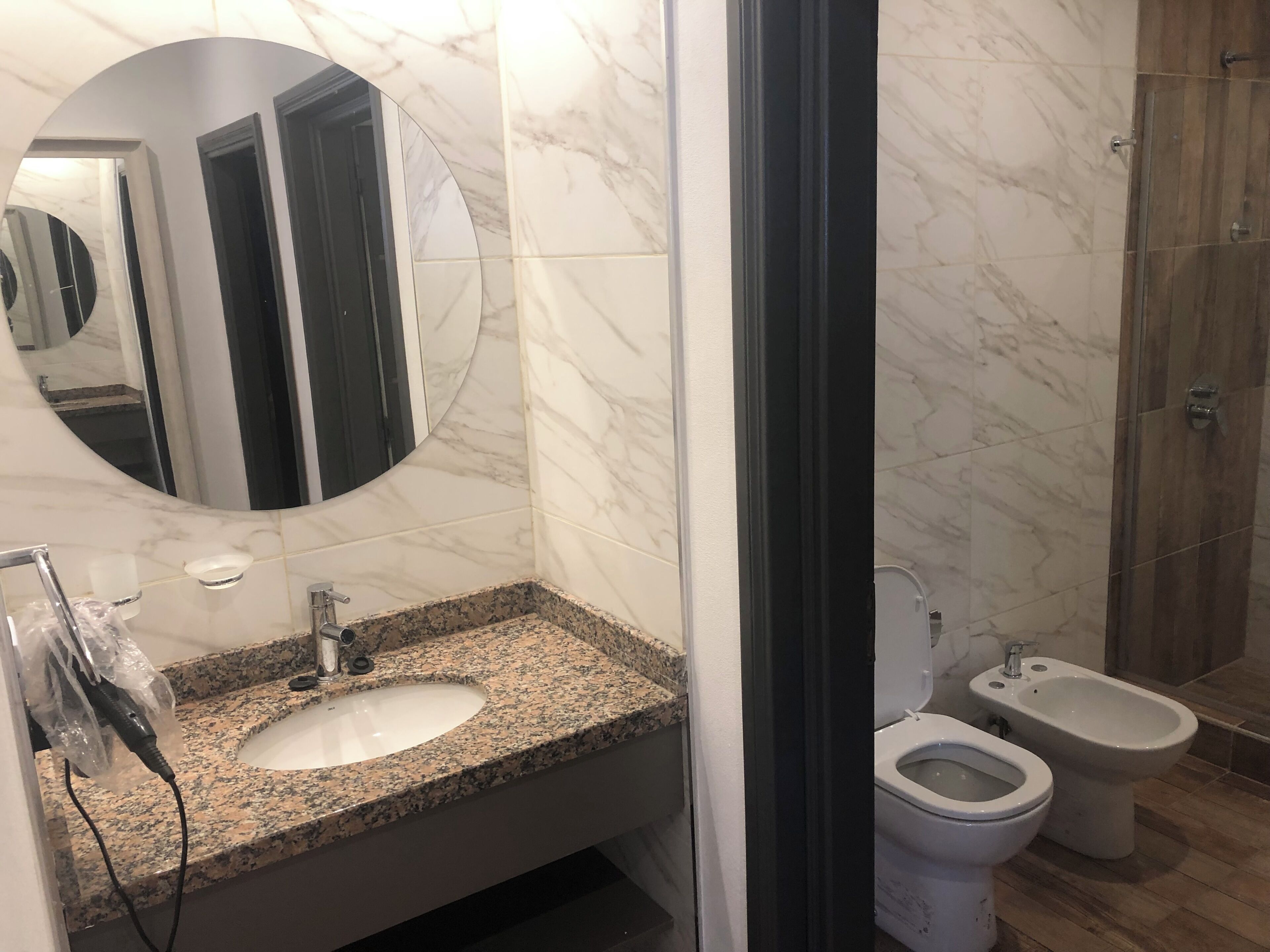 A bathroom with a marble sink, a mirror, a toilet, and a bidet.