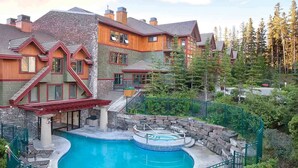 A large building with a pool and hot tub, surrounded by trees. - Cozy 1-bedroom condo in gorgeous Canmore with Indoor/Outdoor Pool and Spa (Canmore)
