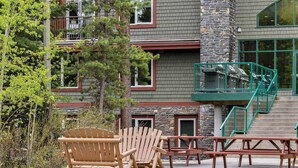 A building with a stone facade, multiple windows, and a staircase leading to an upper level. - Cozy 1-bedroom condo in gorgeous Canmore with Indoor/Outdoor Pool and Spa (Canmore)