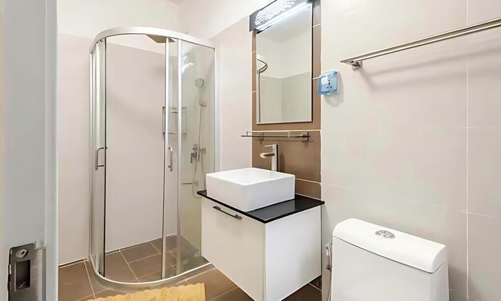 Ein Badezimmer mit Duschkabine aus Glas, einem weißen Waschbecken mit schwarzer Arbeitsplatte und einer weißen Toilette.