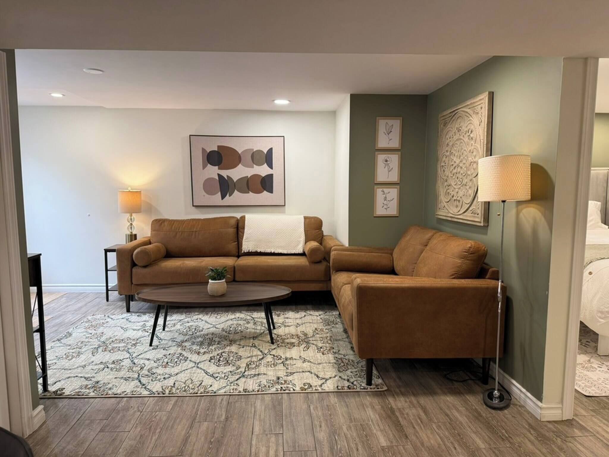 A living room with two brown sofas, a round coffee table, a patterned rug, and a wall with framed artwork.