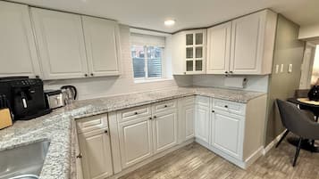 Una cocina con armarios blancos, encimera de granito y una ventana.