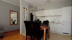 A modern kitchen with white cabinets, a wooden dining table, and black chairs. - Exclusive 2-room apartment in a prime location on Neumarkt (Dresden)