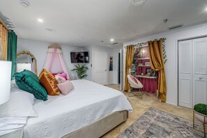 Ein Schlafzimmer mit Bett, Nachttisch, Vorhängen, einem Fernseher und einem Kleiderschrank.