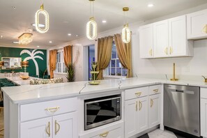 A modern kitchen with white cabinetry, gold handles, a built-in microwave, and a stainless steel dishwasher. - 12 BR Estate!•HeatedPool • Pickle • GameRm •Events (Clearwater)