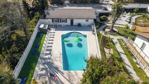 Vue aérienne d’une propriété dotée d’une piscine, de chaises longues et d’un petit bâtiment.