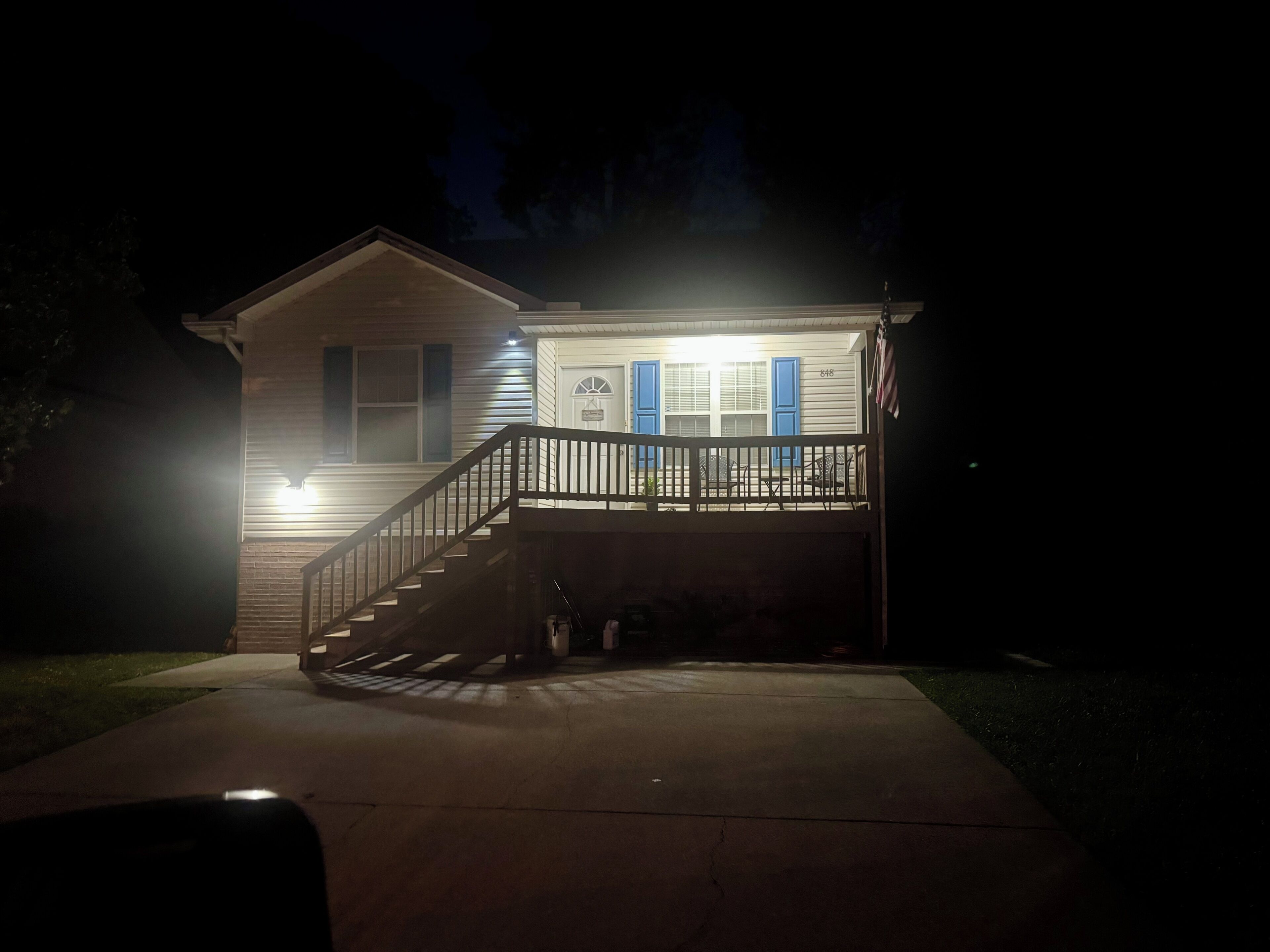 A two-story house with a front porch, a staircase, and a flag.