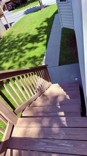 Eine Holztreppe führt zu einem Deck mit einem Rasen und einem Bürgersteig.