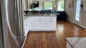 Een keuken met een centraal eiland, een koelkast en een eethoek met een tafel en stoelen.