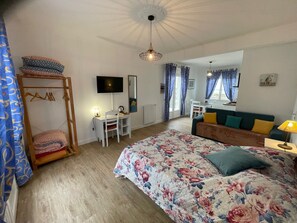 Een slaapkamer met een bed, een bureau, een stoel, een televisie en een hangstoel.