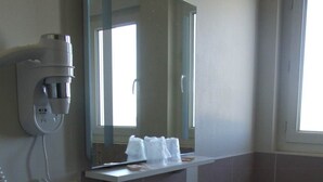 Ein Badezimmer mit Waschbecken, Spiegel und Wandhaartrockner.