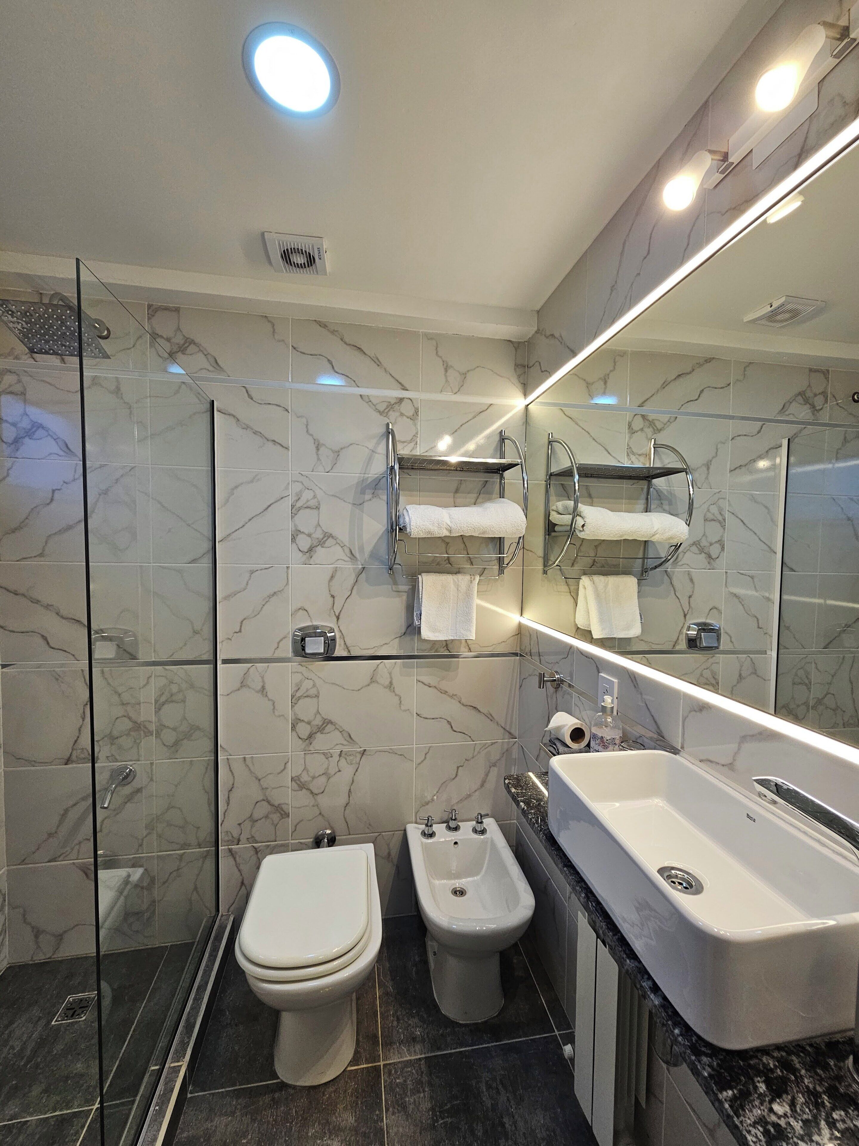 A modern bathroom with a toilet, bidet, and a large sink.