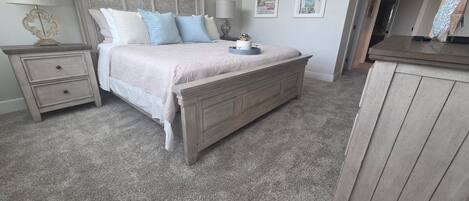 A bedroom with a bed, nightstands, a dresser, and wall art.