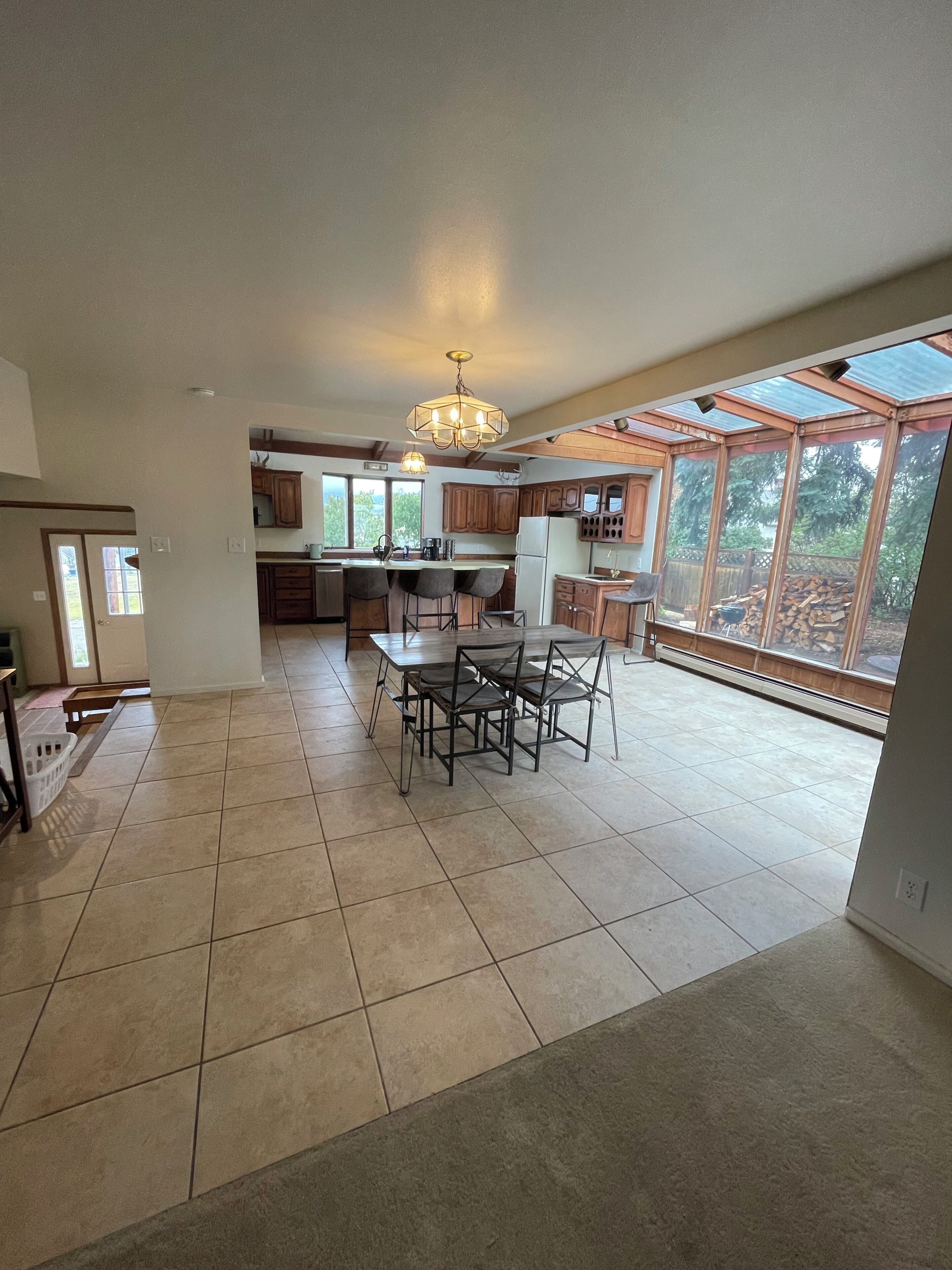 A spacious kitchen with a dining area, large windows, and a view of the outdoors.