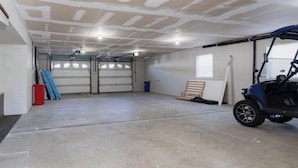 A garage with two closed garage doors, a concrete floor, and a blue golf cart. - New 3BR Wildwood Condo • Sleeps 8 • Garage • Walk to Beach (Wildwood)