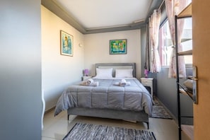 Une chambre à coucher avec un lit, une table de chevet, une lampe et des œuvres d’art accrochées aux murs.