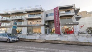A multi-story building with a prominent vertical sign for 'Markopolis.' - A space of comfort and relaxation with a wonderful view and warm hospitality. (Markopoulo Mesogeas)