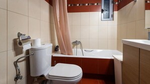 A bathroom with a toilet, bathtub, and a shower curtain. - A space of comfort and relaxation with a wonderful view and warm hospitality. (Markopoulo Mesogeas)
