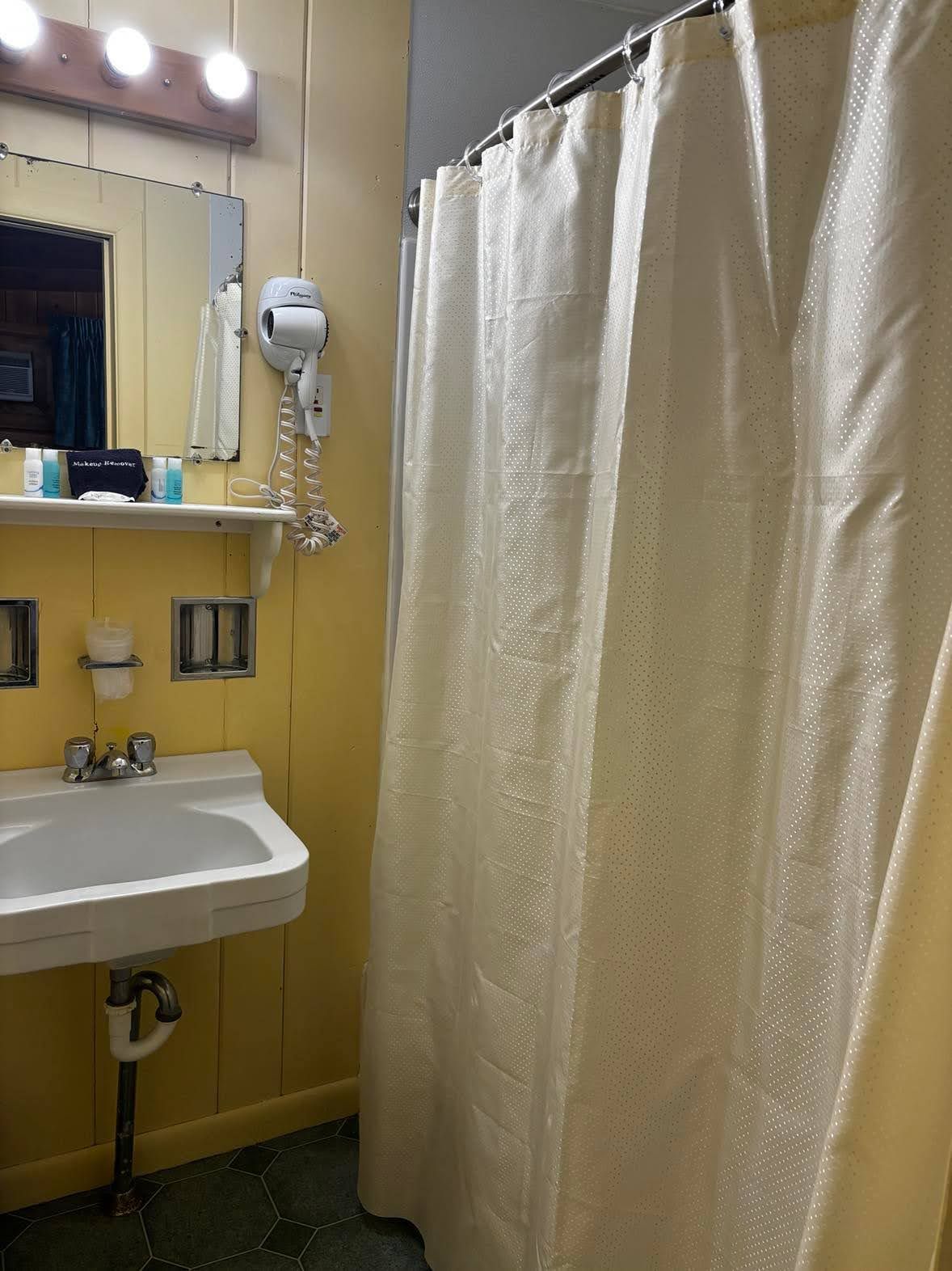 Baño con lavabo, espejo y cortina de ducha.