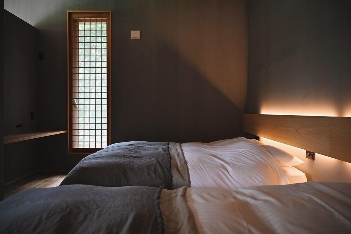 Una habitación con cama, ventana con diseño de celosías y cabecero de madera.