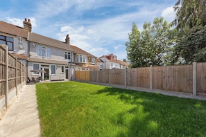A residential area with a well-maintained lawn, a wooden fence, and houses with visible chimneys and windows. - Spacious I Long stays I Sleeps 8 I Free parking (Greater London)
