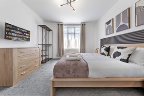Ein modernes Schlafzimmer mit Bett, Kleiderschrank, Fernseher und Bildern an der Wand.