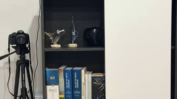 Uma estante com diversos objetos, incluindo livros, uma câmera sobre um tripé e itens decorativos.