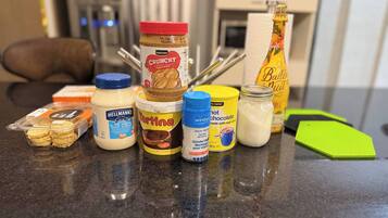 A kitchen counter with various food items including jars of peanut butter, chocolate, and a bottle of wine.